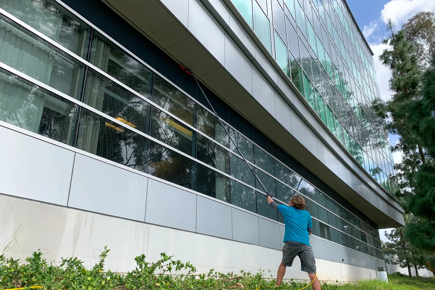 PCS technician using a water-fed pole to clean office-building windows